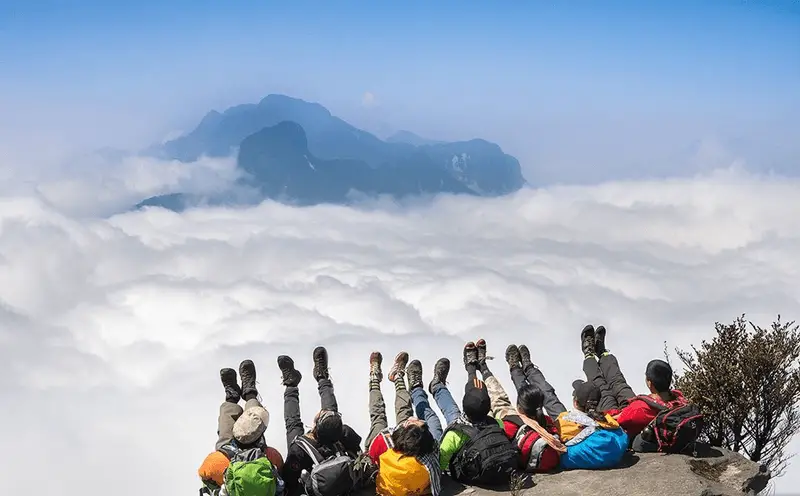 Trekkers resting on the summit of Fansipan above a sea of clouds, the highest peak in Indochina